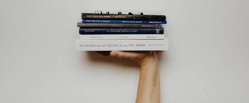 książki trzymane jedną ręką